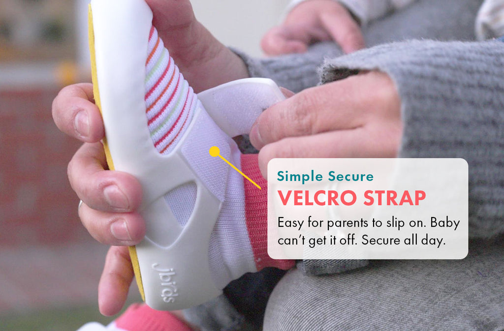 Simple secure velcro strap. Easy for parents to slip on. Baby  can’t get it off. Secure all day.