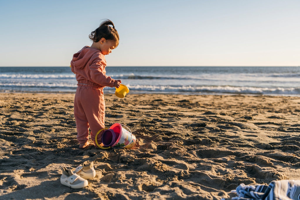 A baby wearing jbrds’ infant walking shoes and playing at the beach. 