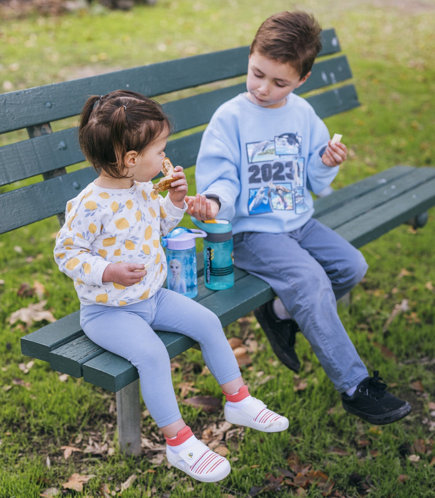 Kids sitting on a bench and exploring outdoors in anatomically designed jbrds toddler shoes.